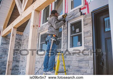 Builder tiling facade of house View Large Photo Image Stock Photo - Builder tiling facade of house. Fotosearch