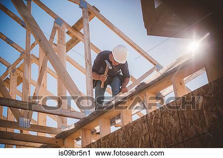 Builder working on rooftop frame of building View Large Photo Image Stock Image - Builder working on rooftop frame of building. Fotosearch