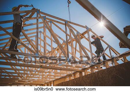 Builders working on rooftop frame of building View Large Photo Image Stock Image - Builders working on rooftop frame of building. Fotosearch