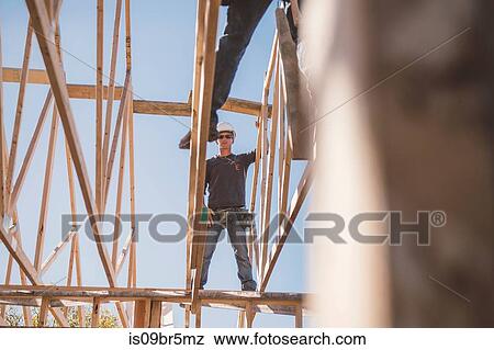 Builders working on rooftop frame of building View Large Photo Image Stock Photo - Builders working on rooftop frame of building. Fotosearch