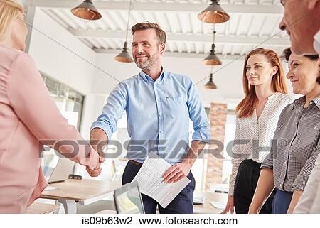 Stock Image - Business people in office shaking hands. Fotosearch