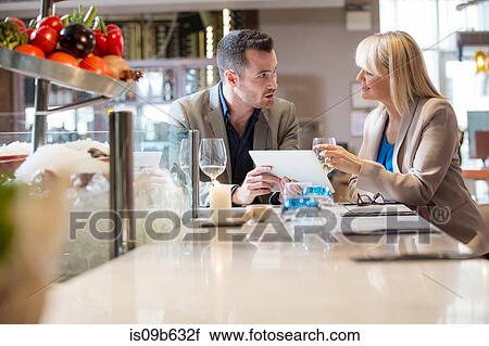 Stock Image - Businessman and businesswoman at lunch in restaurant. Fotosearch