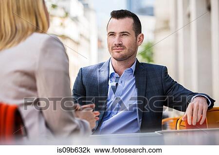 Stock Image - Businessman and businesswoman at sidewalk cafe. Fotosearch
