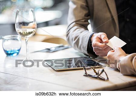 Stock Image - Businessman and businesswoman making introductions at lunch in restaurant. Fotosearch