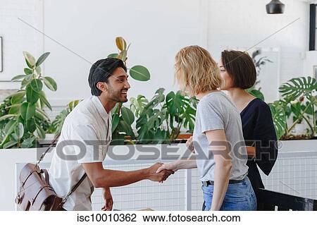 Stock Image - Businessman and businesswoman shaking hands in office. Fotosearch