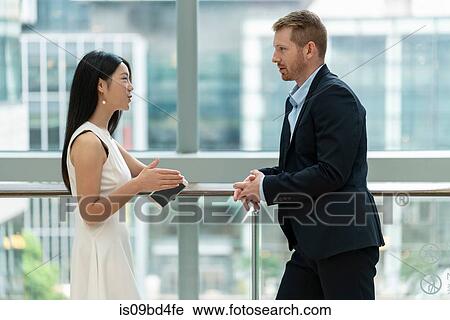 Businessman and businesswoman standing beside window, in conversation View Large Photo Image Stock Image - Businessman and businesswoman standing beside window, in conversation. Fotosearch