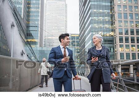 Businessman and businesswoman using mobile phone and pulling trolley luggage, Canary Wharf, London, UK View Large Photo Image Stock Image - Businessman and businesswoman using mobile phone and pulling trolley luggage, Canary Wharf, London, UK. Fotosearch