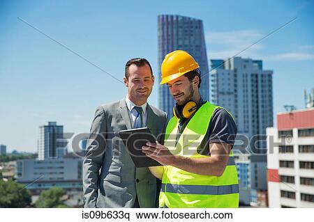 Stock Photography - Businessman and construction worker, outdoors, looking at digital tablet. Fotosearch