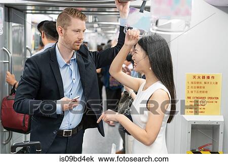 Businessman and woman standing on train, in conversation View Large Photo Image Stock Image - Businessman and woman standing on train, in conversation. Fotosearch