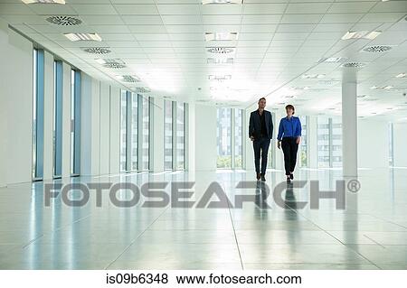 Businessman and woman walking through empty office space View Large Photo Image Stock Photo - Businessman and woman walking through empty office space. Fotosearch