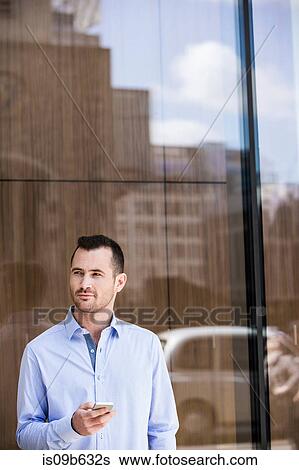 Stock Photograph - Businessman in front of glass building, London, UK. Fotosearch