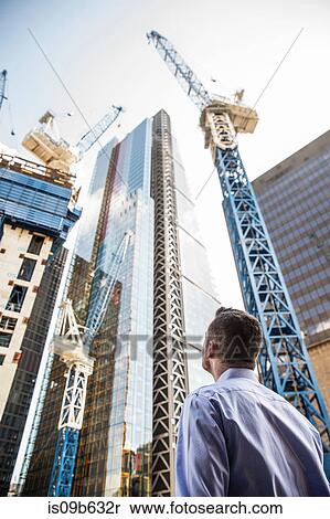 Stock Photography - Businessman looking up at building under construction, London, UK. Fotosearch