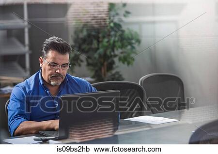 Stock Image - Businessman using laptop in office. Fotosearch