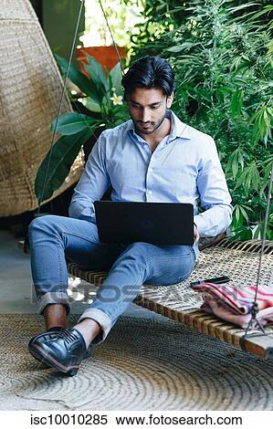 Businessman using laptop on swing View Large Photo Image Stock Photography - Businessman using laptop on swing. Fotosearch