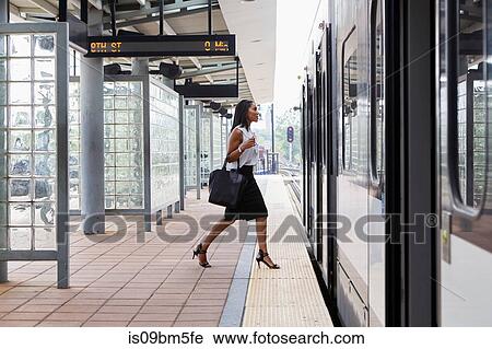 Stock Image - Businesswoman boarding train. Fotosearch