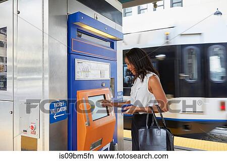 Picture - Businesswoman buying train ticket at machine. Fotosearch