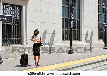 Businesswoman checking time by light rail line View Large Photo Image Picture - Businesswoman checking time by light rail line. Fotosearch