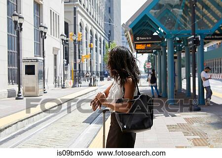 Businesswoman checking time by light rail line View Large Photo Image Picture - Businesswoman checking time by light rail line. Fotosearch