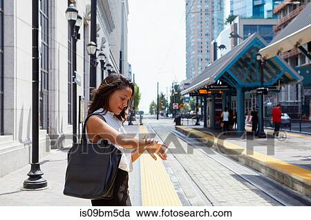 Businesswoman checking time by light rail line View Large Photo Image Stock Image - Businesswoman checking time by light rail line. Fotosearch