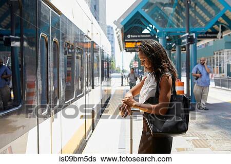 Businesswoman checking time by light rail line View Large Photo Image Stock Photograph - Businesswoman checking time by light rail line. Fotosearch