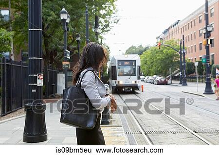 Businesswoman checking time by light rail line View Large Photo Image Stock Photograph - Businesswoman checking time by light rail line. Fotosearch