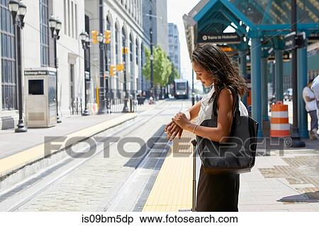Businesswoman checking time by light rail line View Large Photo Image Stock Photography - Businesswoman checking time by light rail line. Fotosearch