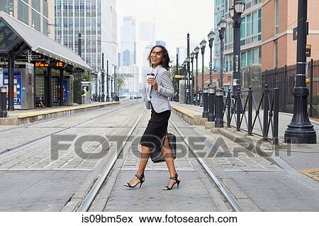 Stock Photo - Businesswoman crossing light rail tracks. Fotosearch