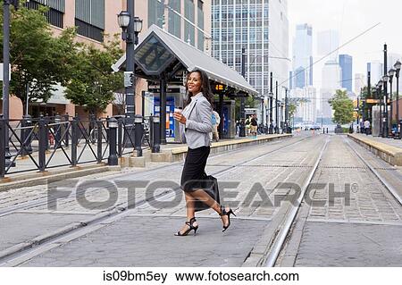 Stock Photo - Businesswoman crossing light rail tracks. Fotosearch