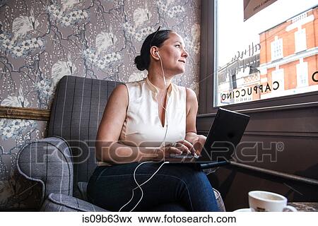 Businesswoman in coffee bar looking through window with laptop View Large Photo Image Stock Photo - Businesswoman in coffee bar looking through window with laptop. Fotosearch