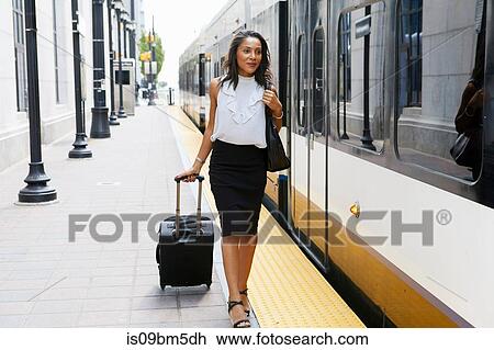 Businesswoman pulling luggage alongside train View Large Photo Image Stock Image - Businesswoman pulling luggage alongside train. Fotosearch