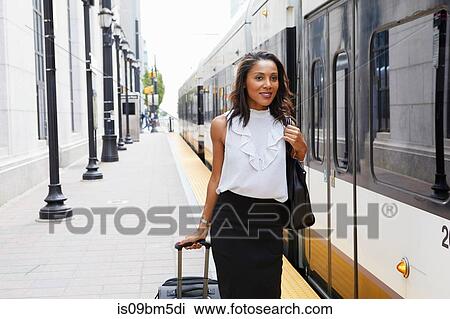Businesswoman pulling luggage alongside train View Large Photo Image Stock Image - Businesswoman pulling luggage alongside train. Fotosearch