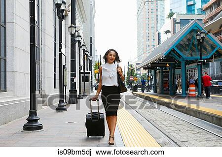 Businesswoman pulling luggage alongside train View Large Photo Image Stock Image - Businesswoman pulling luggage alongside train. Fotosearch