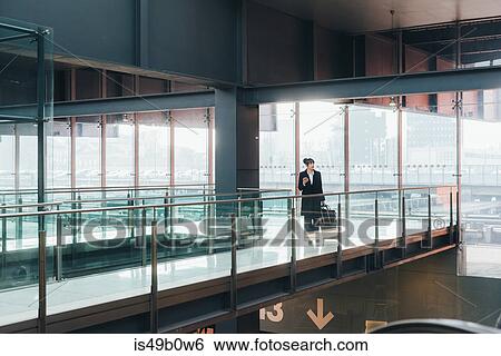 Stock Photograph - Businesswoman pulling trolley luggage, Milan, Italy. Fotosearch