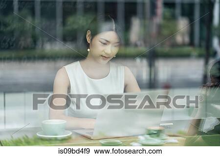 Businesswoman sitting in cafe, using laptop, viewed through window View Large Photo Image Stock Photo - Businesswoman sitting in cafe, using laptop, viewed through window. Fotosearch