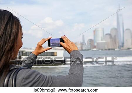 Stock Photograph - Businesswoman taking photograph of New York City skyline. Fotosearch