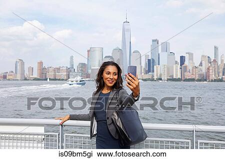 Stock Image - Businesswoman taking selfie, New York, US. Fotosearch