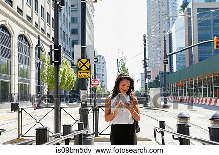 Stock Photo - Businesswoman using cellphone by barriers. Fotosearch