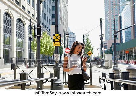 Stock Photo - Businesswoman using cellphone by barriers. Fotosearch
