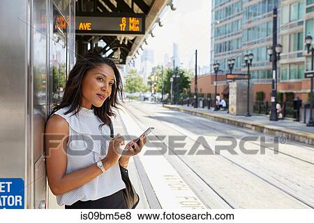 Businesswoman using cellphone by ticket machine View Large Photo Image Stock Photo - Businesswoman using cellphone by ticket machine. Fotosearch