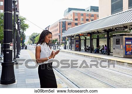 Businesswoman using cellphone in light rail station View Large Photo Image Stock Image - Businesswoman using cellphone in light rail station. Fotosearch