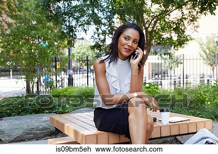 Businesswoman using cellphone in park View Large Photo Image Stock Image - Businesswoman using cellphone in park. Fotosearch
