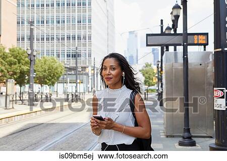 Stock Image - Businesswoman using cellphone in street. Fotosearch