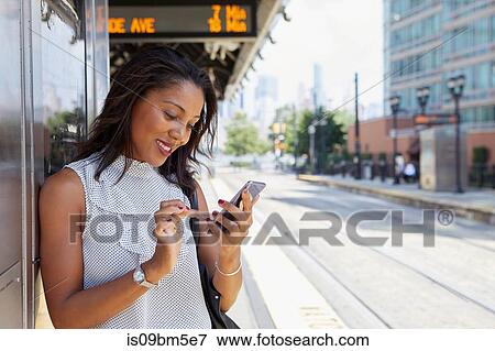 Stock Photo - Businesswoman using cellphone in train station. Fotosearch