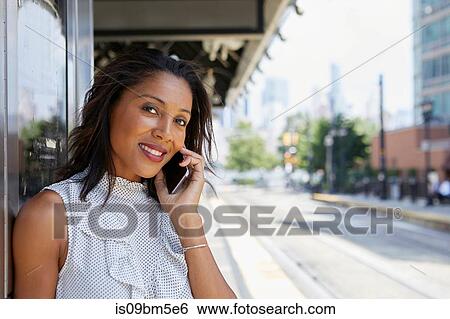 Stock Photograph - Businesswoman using cellphone in train station. Fotosearch