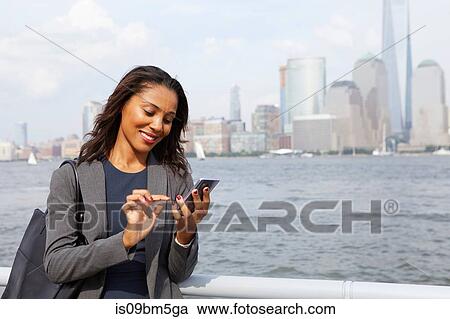 Businesswoman using cellphone, New York City skyline in background View Large Photo Image Stock Image - Businesswoman using cellphone, New York City skyline in background. Fotosearch