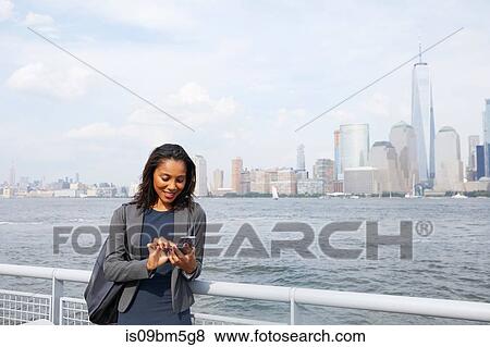 Businesswoman using cellphone, New York City skyline in background View Large Photo Image Stock Photo - Businesswoman using cellphone, New York City skyline in background. Fotosearch