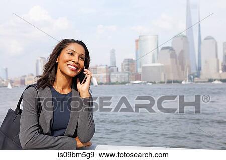 Businesswoman using cellphone, New York City skyline in background View Large Photo Image Stock Photo - Businesswoman using cellphone, New York City skyline in background. Fotosearch
