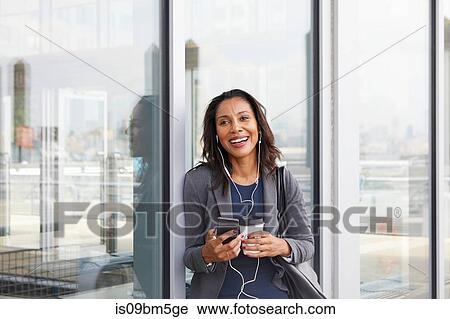 Stock Image - Businesswoman using cellphone outside ferry terminal. Fotosearch
