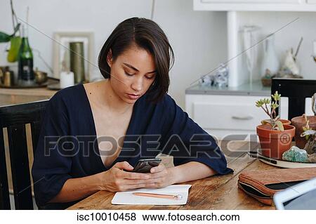 Stock Photo - Businesswoman using cellular phone in office. Fotosearch