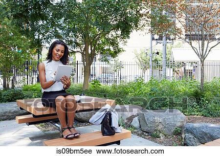 Businesswoman using digital tablet in park View Large Photo Image Stock Image - Businesswoman using digital tablet in park. Fotosearch